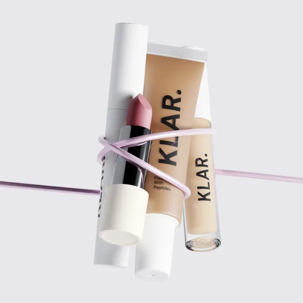 Lippenbalsam- und Gloss-Tuben der Marke Klar, zusammengebunden mit einem rosa Band.