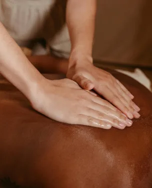 Nahaufnahme von Händen, die während einer Spa-Behandlung eine Rückenmassage geben.
